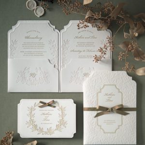 Florale Einladungskarte zur Hochzeit mit Pockethülle und zwei Einlegekarten in der Papierfarbe Leinenweiß. Die Karten sind alle mit einem floralen Muster farblos geprägt und in salbeigrünem Text bedruckt.
