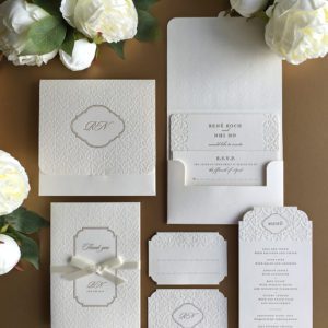 Eine einzigartige Hochzeitseinladung mit quadratischen Pockethülle, die eine Einladungskarte und eine Zusatzkarte mit Informationen für die Hochzeit beinhaltet. Zu der Hochzeits-Kollektion gehören auch Letterpress-Dankeskarten mit einem Satinband, Menükarten für die Feier und Namenkarten