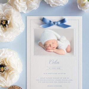 Eine weiße Letterpress Geburtskarte im A5 Format für Buben in Blau bedruckt, mit eined zarten Satinschleife in Rauchblau und einem entzückendem Baby-Foto
