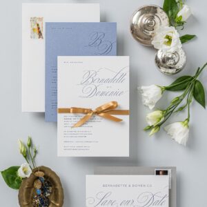 Modern elegante Hochzeitseinladung auf weißen Baumwollpapier mit rauchblauer Druckfarbe gedruckt. Ein goldenens Satinband verbindet die Einladungskarte mit der blauen Zusatzkarte.