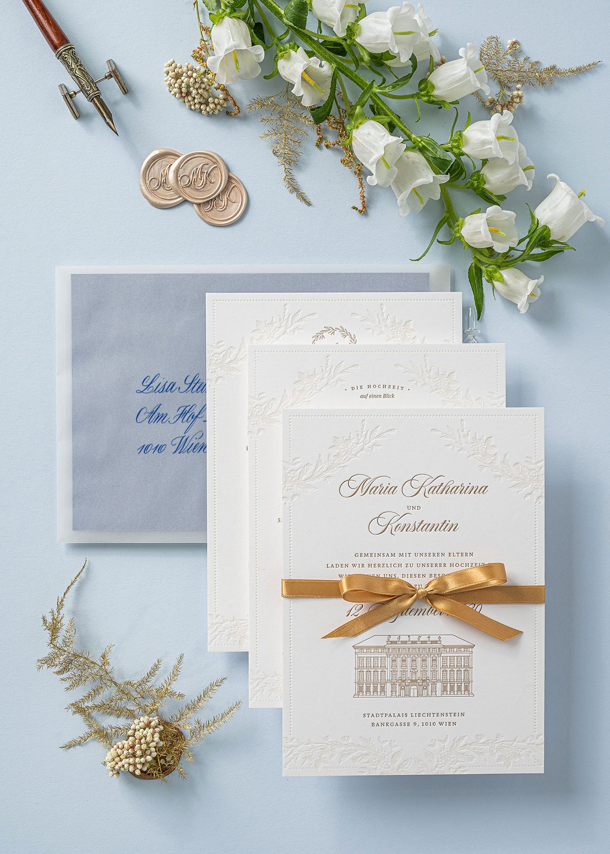 Florale Letterpress Hochzeitseinladung mit goldener Druckfarbe für den Text und eine Illustration für das Palais Liechtenstein. Die A5 Karte ziert auch ein goldenes Satinband und das Kuvert ist mit Kalligrafie beschriftet