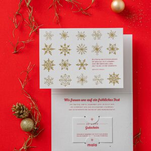 Edle Letterpress Weihnachtskarte mit Schneeflocken in glänzender Goldfolie geprägt auf der Vorderseite der Klappkarte. In der Karte stecket ein Geschenkgutschein, die man rausnehmen kann. Der Text ist in Pantone Rot bedruckt.