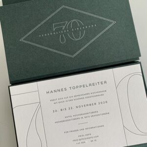 Exklusive Letterpress Einladungskarten zum 70. Geburtstag in einer grünen pockethülle mit Prägung, einer eingeklebter bedruckter Karte im Inneren sowie einer Zusatz-Informationskarte in der Tasche