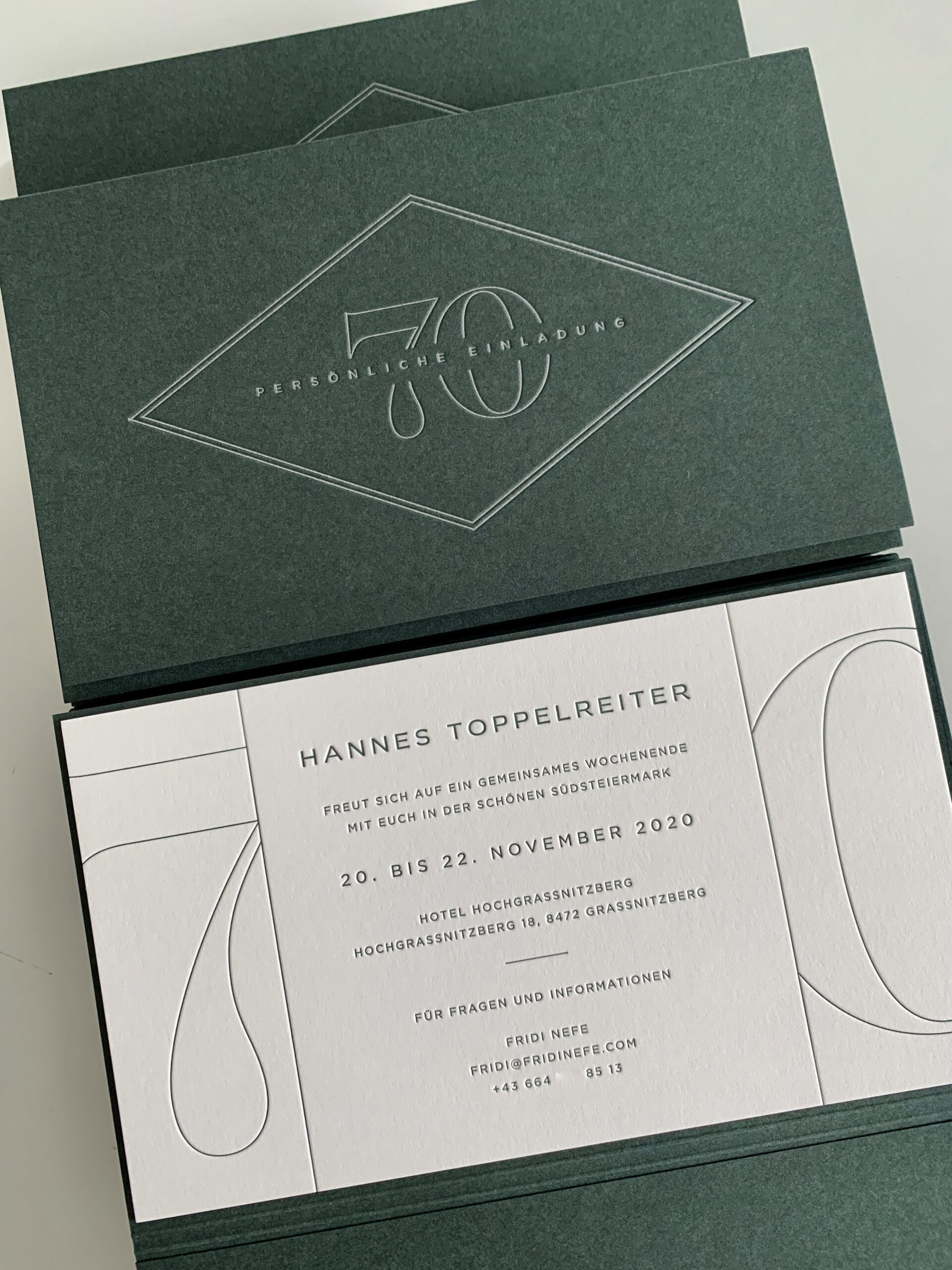 Exklusive Letterpress Einladungskarten zum 70. Geburtstag in einer grünen pockethülle mit Prägung, einer eingeklebter bedruckter Karte im Inneren sowie einer Zusatz-Informationskarte in der Tasche