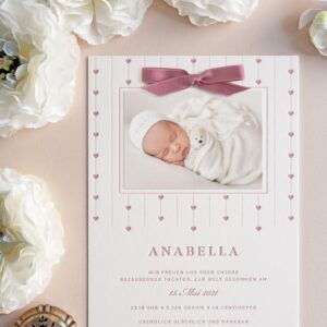 Eine Weiße Letterpress Geburtsanzeige für Maedchen, die mit wiederholenden pünktchen und Herzornamenten in Rosa rund um das Babyfoto bedruckt worden ist - es ist das Design B112