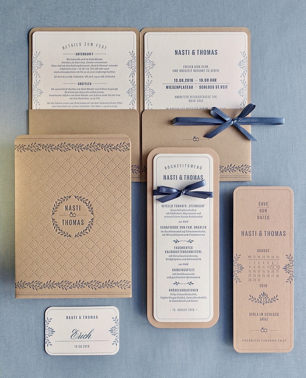 Letterpress Hochzeitseinladungen »Pocketfold« mit bedruckter Hülle im floralen Design und Punktelinien-Rahmen auf Natur-Karton. In der Hülle stecken verschiedene Einlegekarten, die in Rauchblau bedruckt sind.