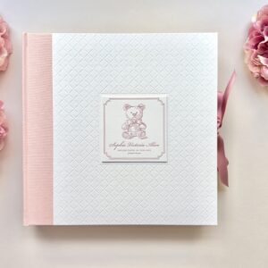 Handgebundenes Fotoalbum Unikat mit Letterpress Einband aus weißem Baumwoll-Papier mit Ornament-Prägung und quadratischem Vignette, die mit Vintage-Teddy und Text in Rosa bedruckt ist