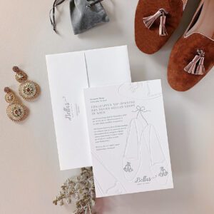 Eine weiße Letterpress Eventeinladung in grau bedruckt und farblos geprägt zur Shoperöffnung von »Bellas Made in Italy« Schuhe mit Tasseln